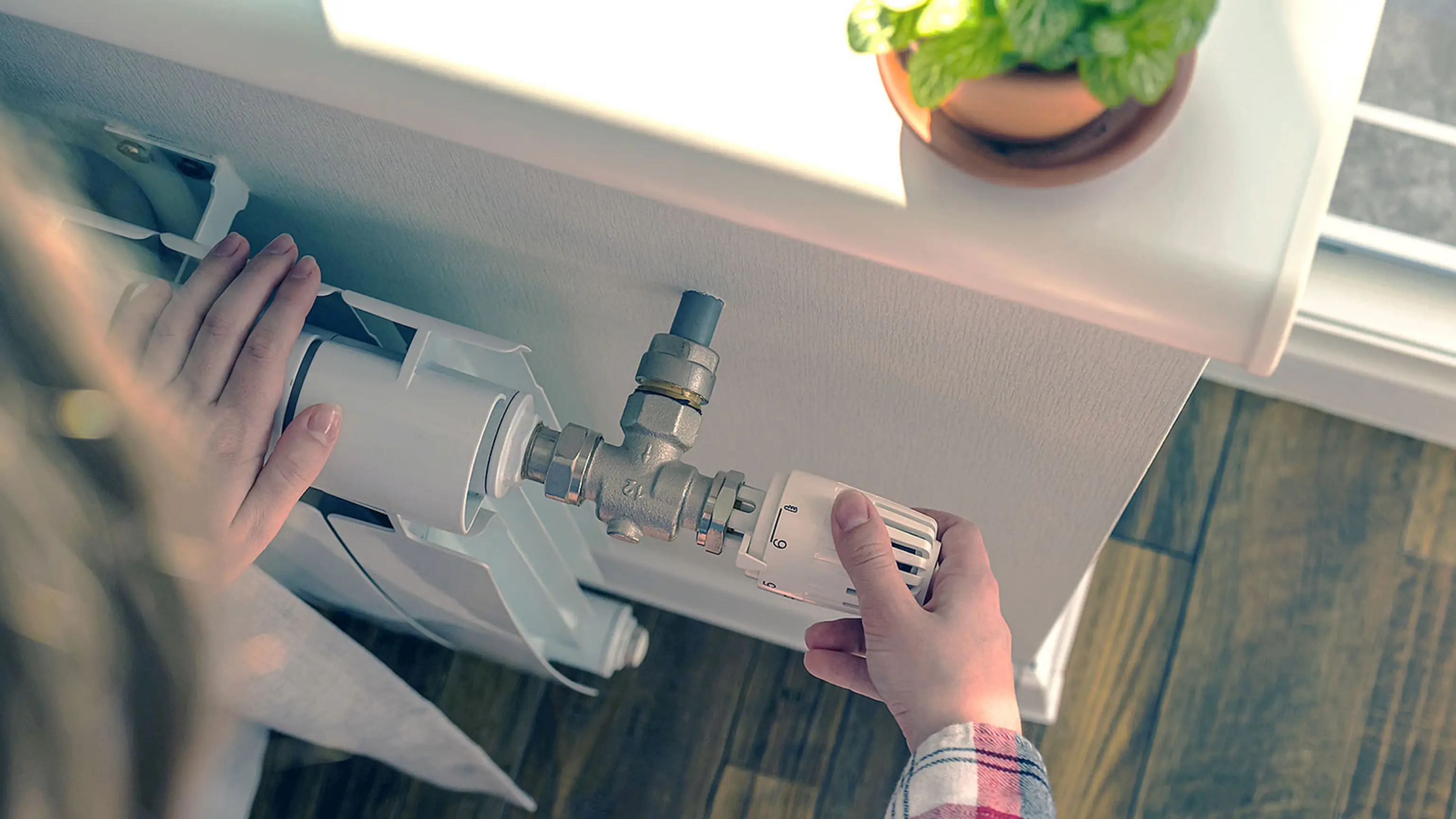 Frau stellt Temperatur am Heizkörper ein