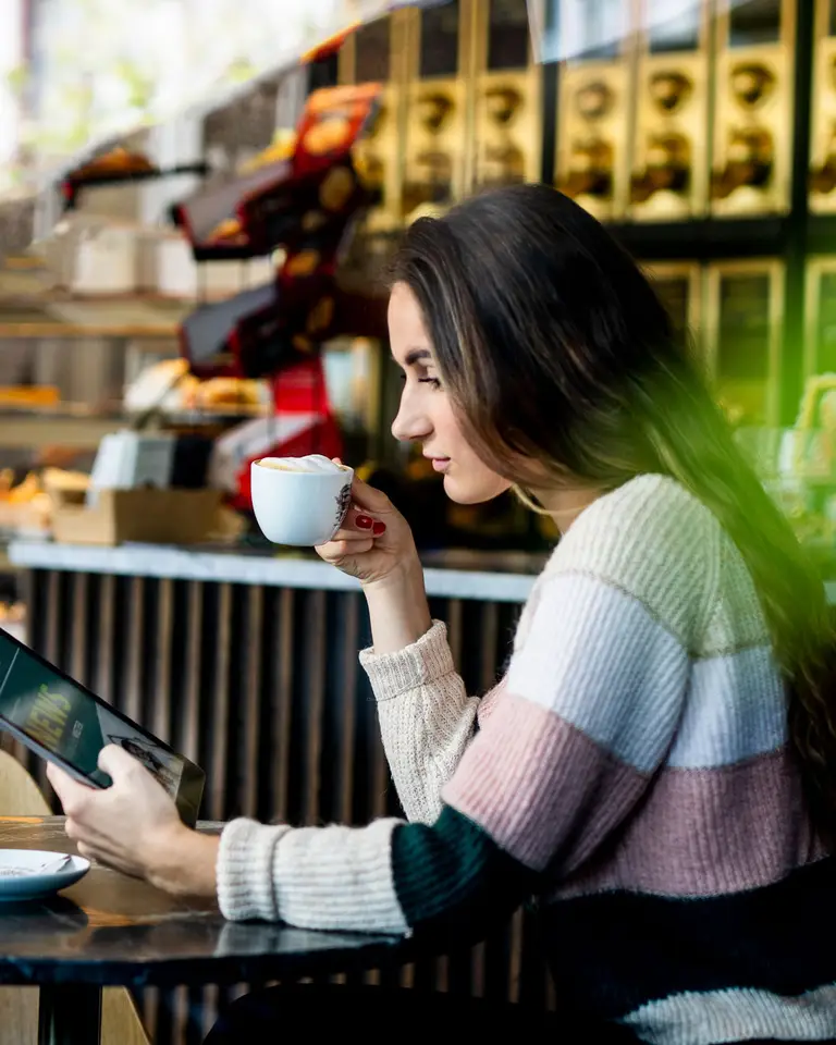 Frau ließt in einem Kaffeehaus auf Ihrem Tablet News zur GWH