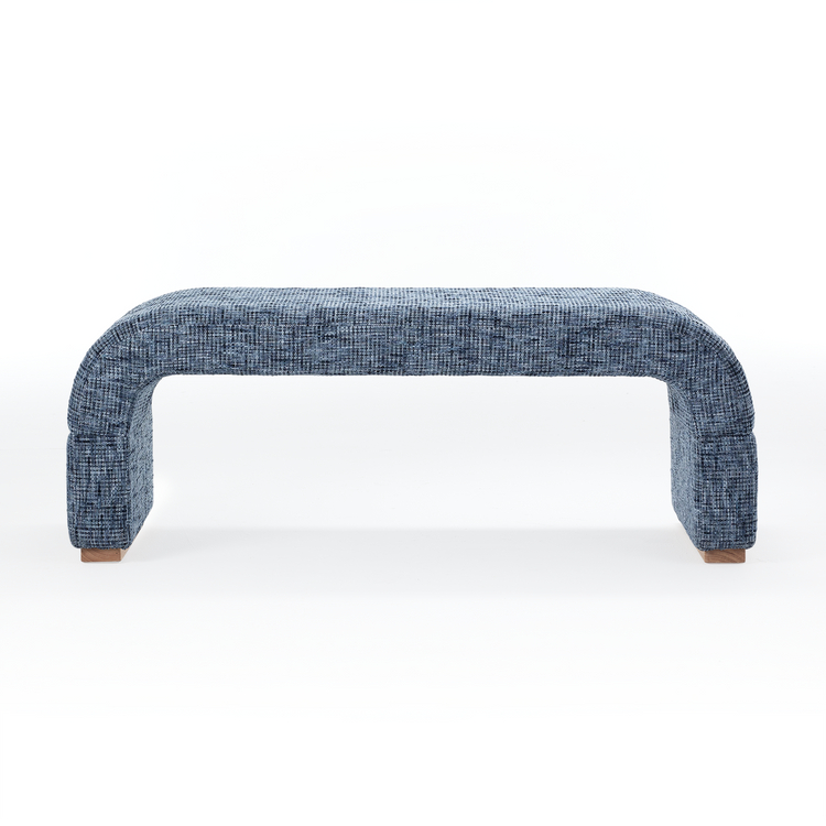 A blue plaid upholstered bench has rounded waterfall sides, Small brown feet appear beneath both ends