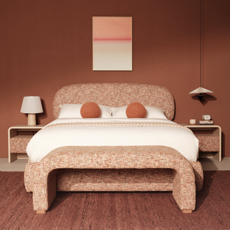 A rounded upholstered bed and matching bench share the same warm multitone surface pattern