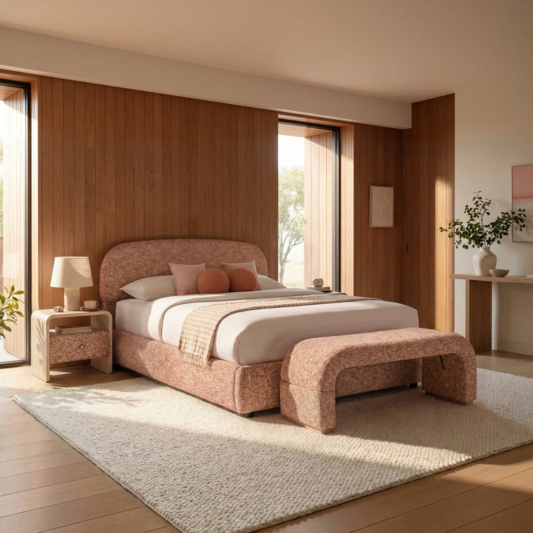 Rust upholstered bed with rounded headboard anchors a sunlit bedroom, A matching curved bench stands at the foot