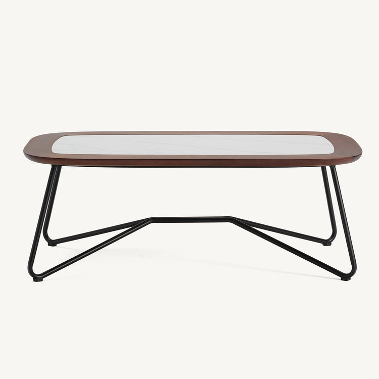 Long low coffee table has a pale veined inset, dark rounded frame, and crossed tubular legs