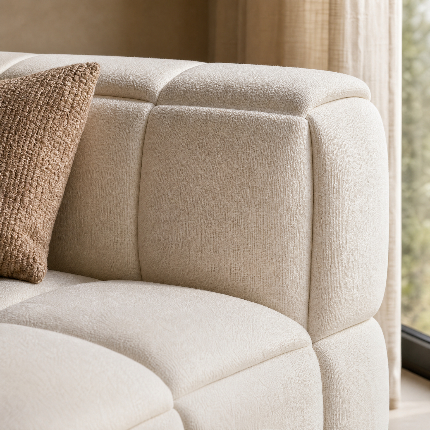 Close-up of a sofa corner with broad padded sections and a textured pillow