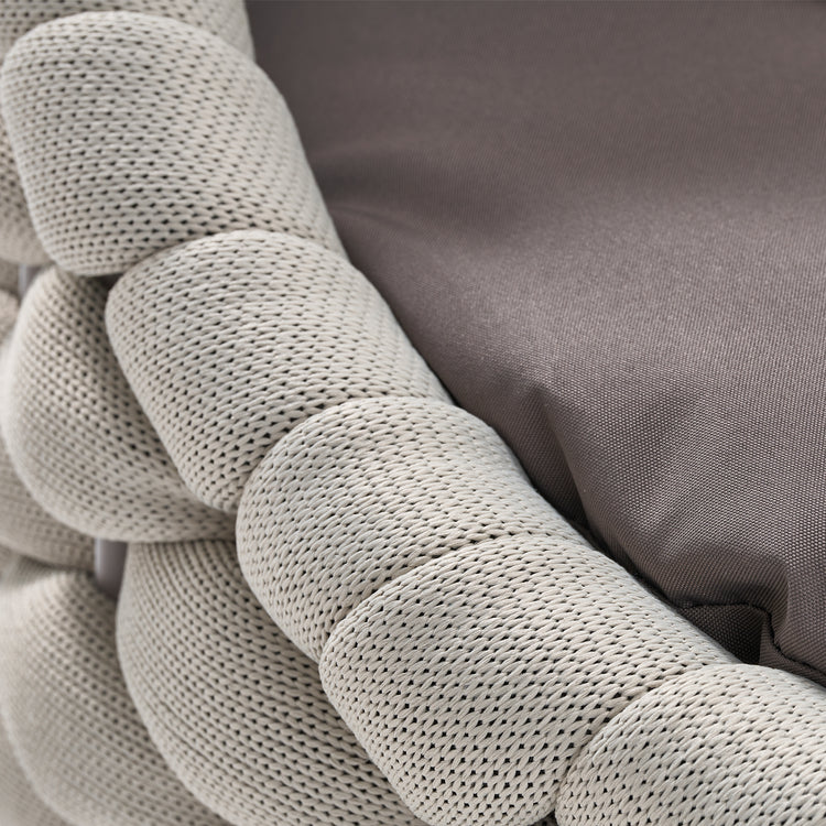 Macro close-up of a pale woven cord furniture frame beside a gray fabric cushion
