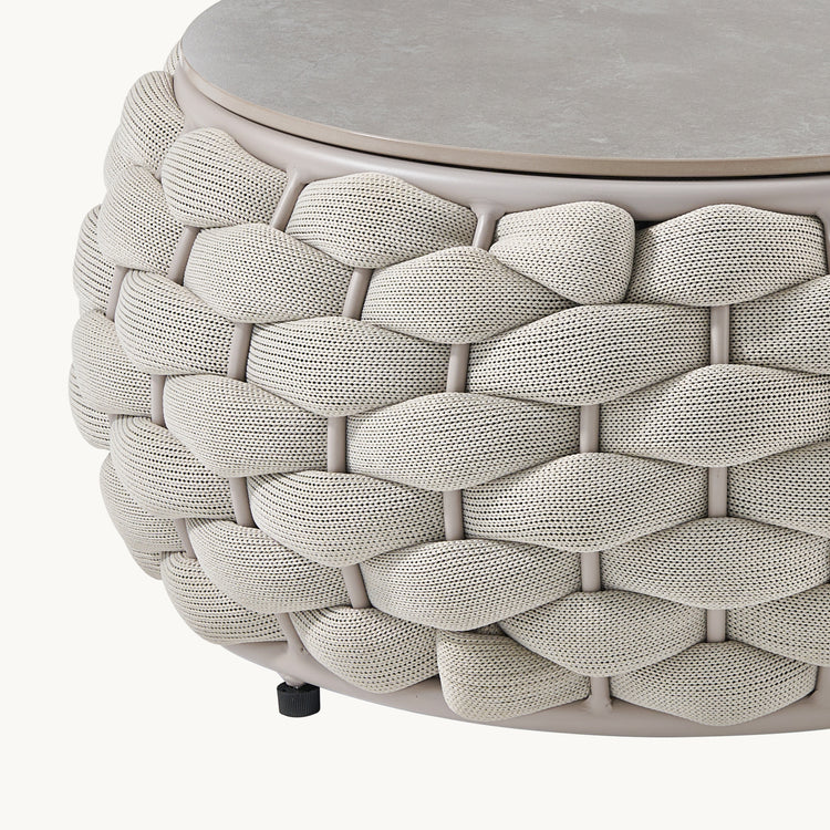 A close-up shows a round tabletop above a basket-weave body formed by thick braided strands
