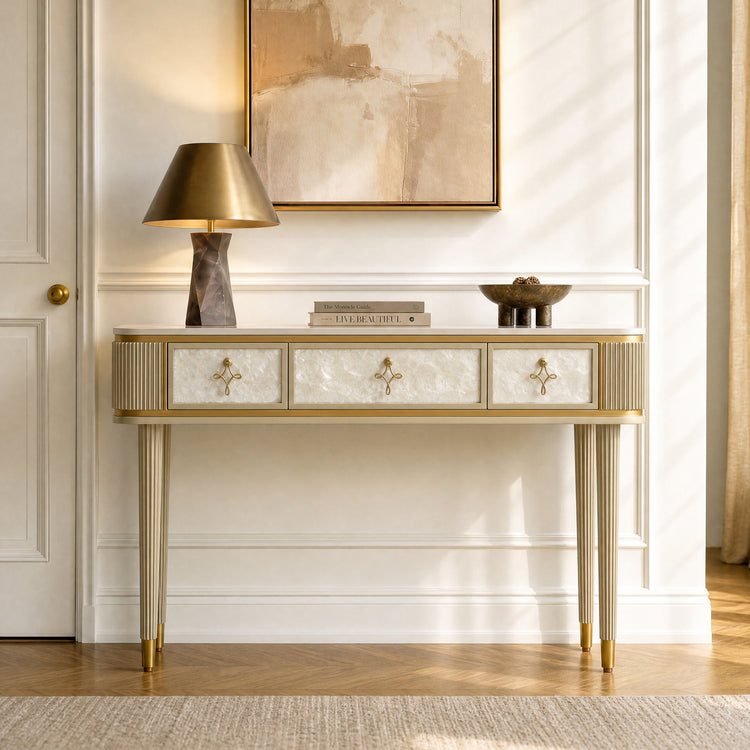 Gold-toned console table has three pale textured drawers and four slim fluted legs