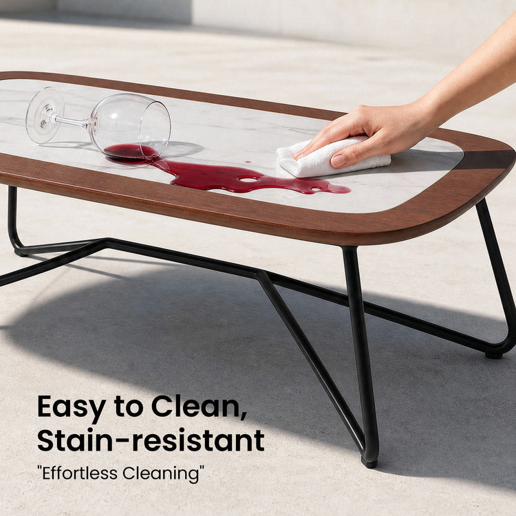 A hand wipes spilled red liquid from the light inset tabletop