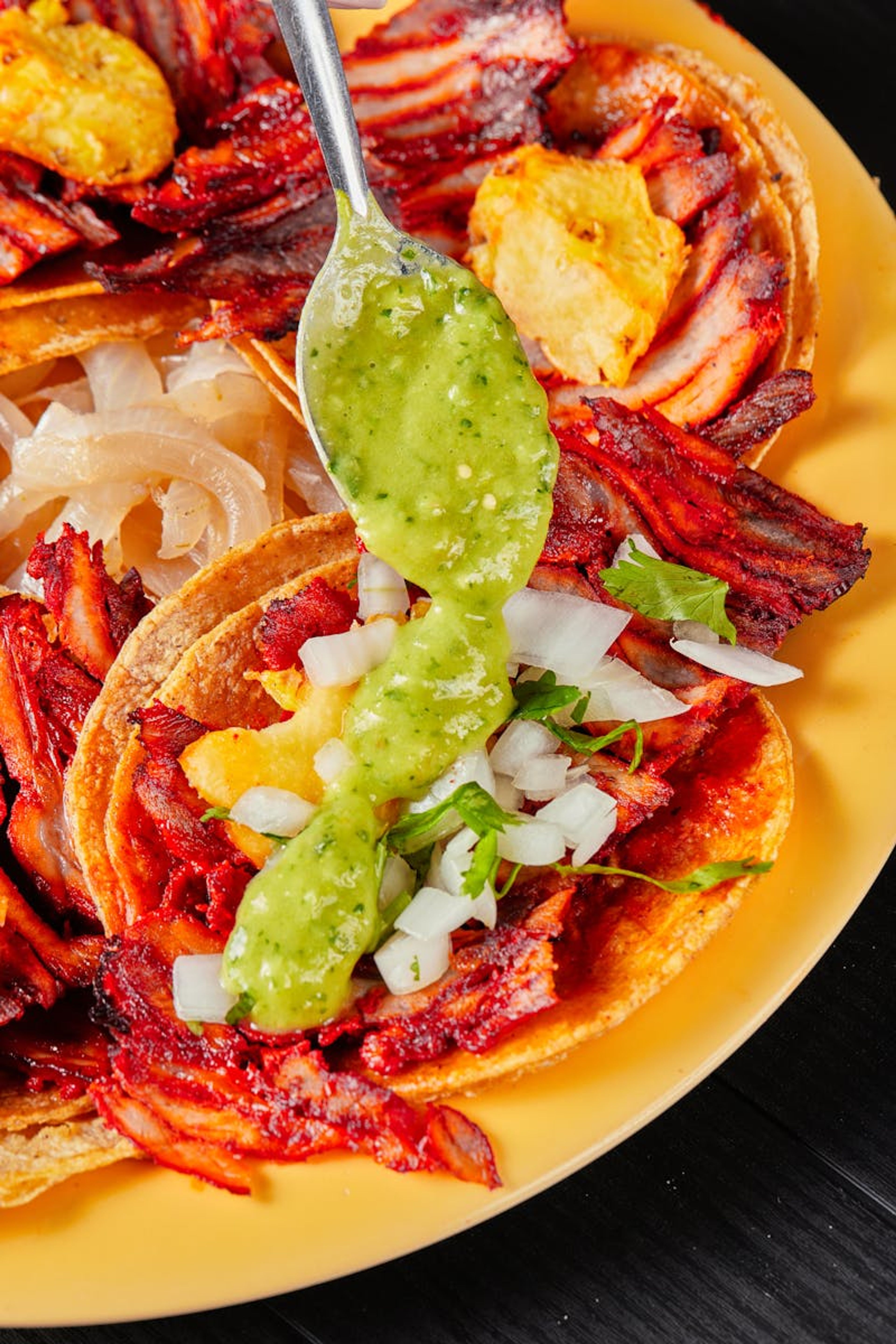Tres tacos al pastor con carne marinada, piña y cilantro fresco.