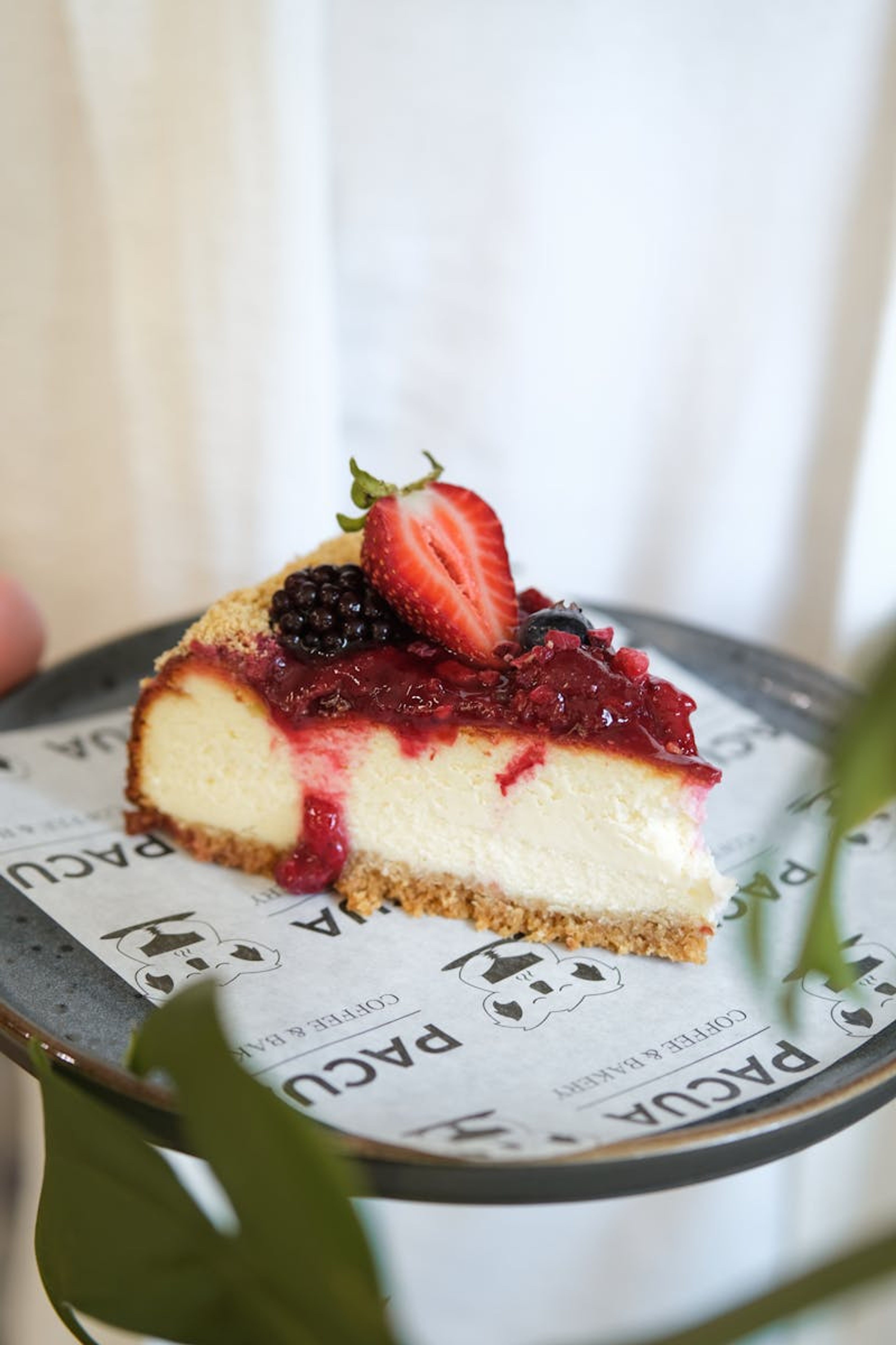 Rebanada de cheesecake cremoso cubierto con mermelada de frutos rojos.