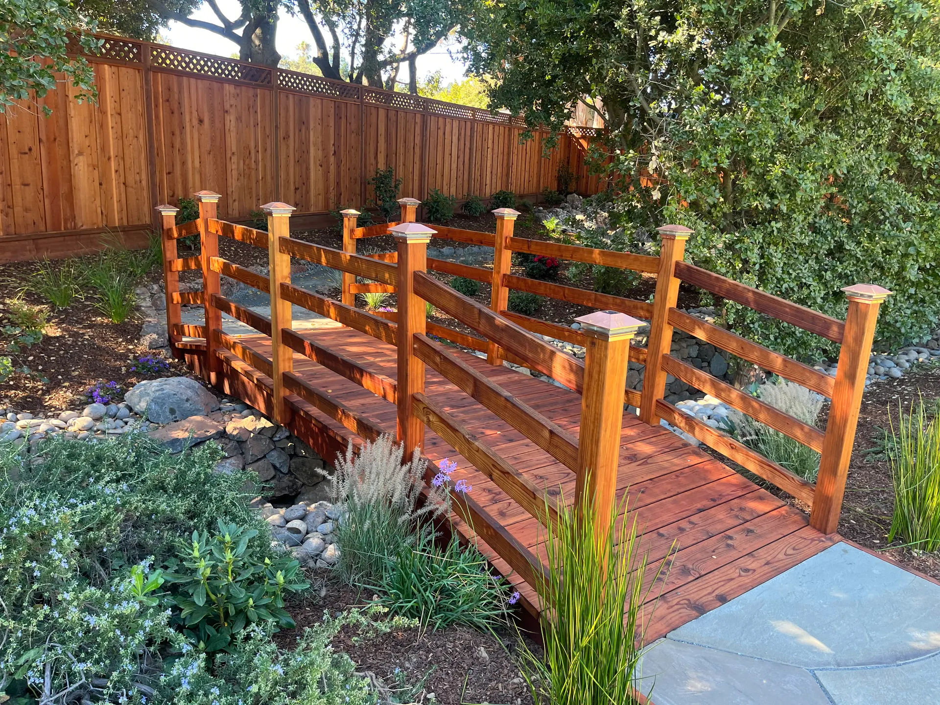 Custom hardscape bridge and wood outdoor feature by Garcia's Landscaping