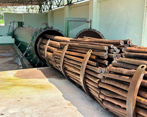 Uma pilha de troncos de eucalipto tratado, com superfície uniforme e cortada, está empilhada em camadas