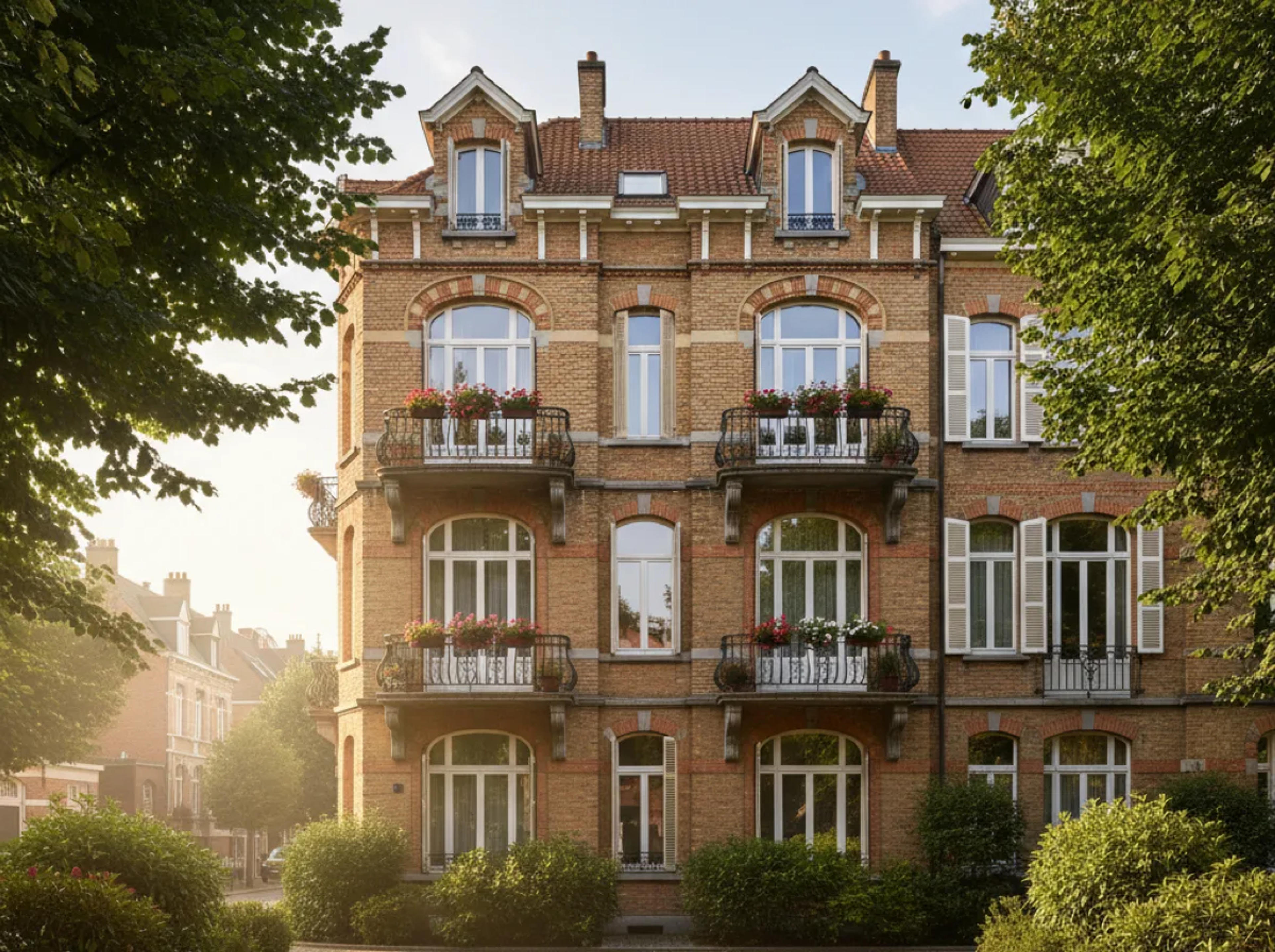 Façade d’un immeuble à appartements en briques, balcons en fer forgé garnis de fleurs et fenêtres à châssis blancs, encadré par des arbres Façade d’un immeuble à appartements en briques, balcons en fer forgé garnis de fleurs et fenêtres à châssis blancs, encadré par des arbres