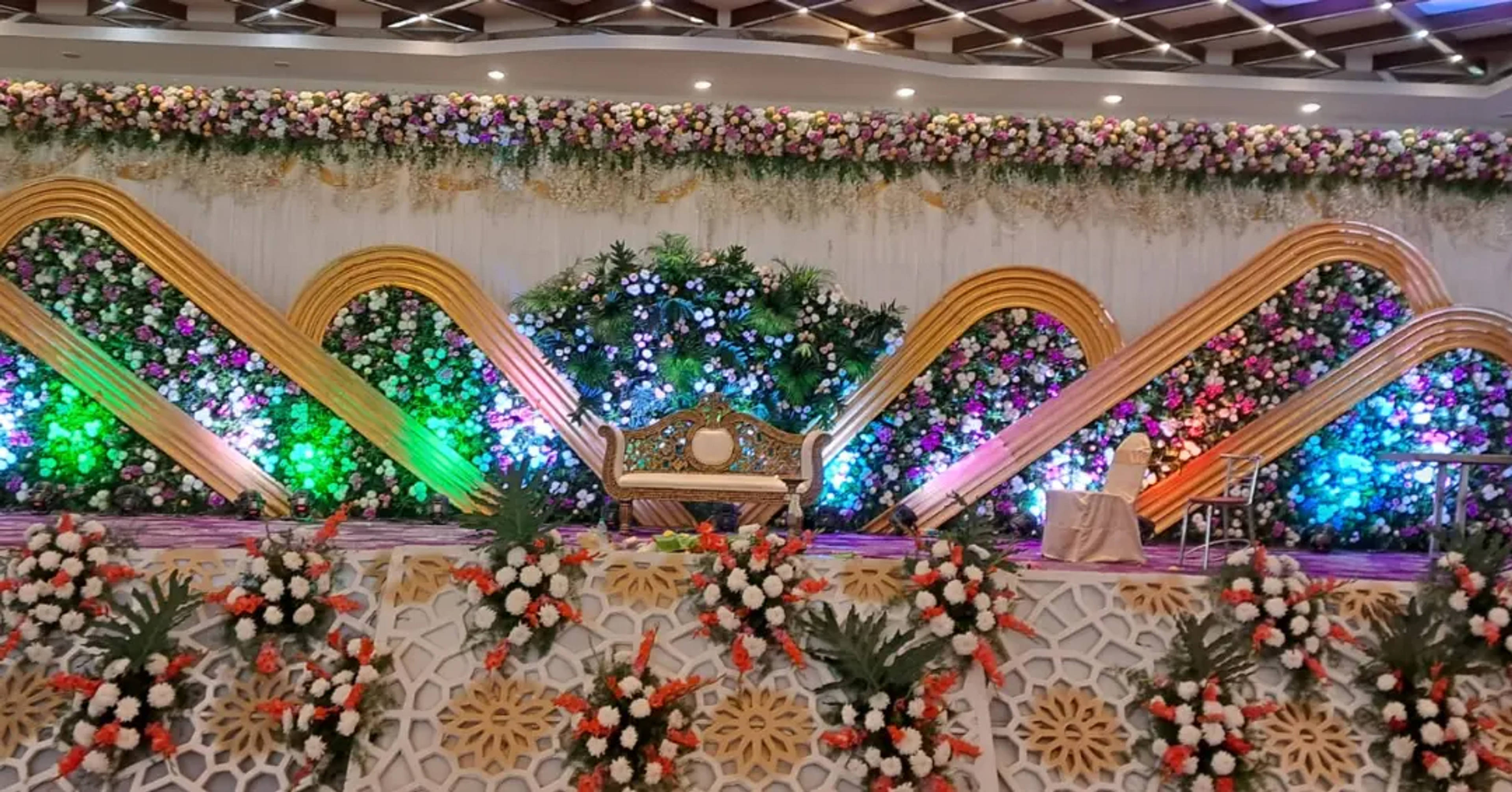 Row of illuminated floral arches forming a wide wedding stage
