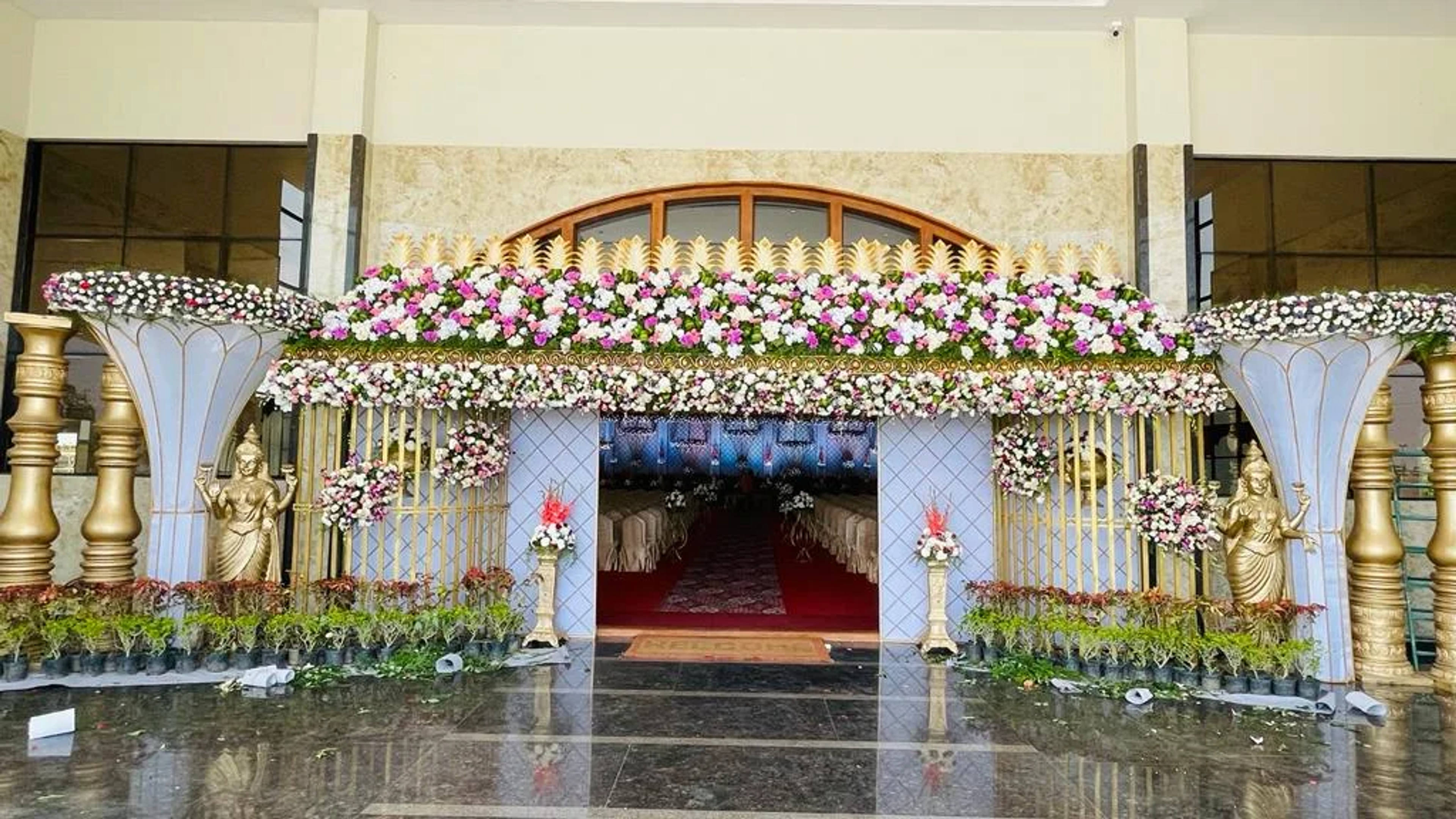 White colonnade stage with brass deities and a floral canopy