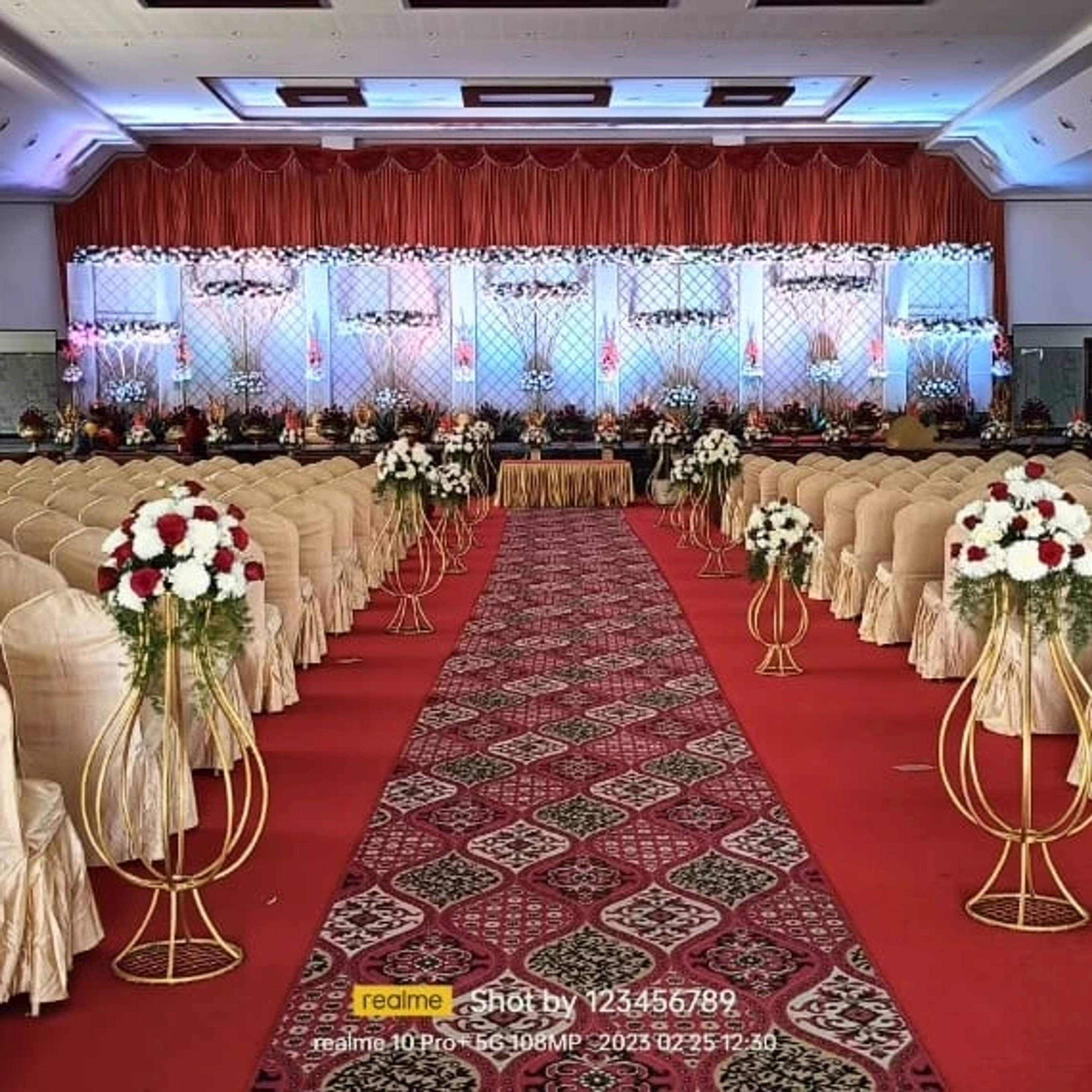 Reception aisle dressed with tall flower stands and draped chairs