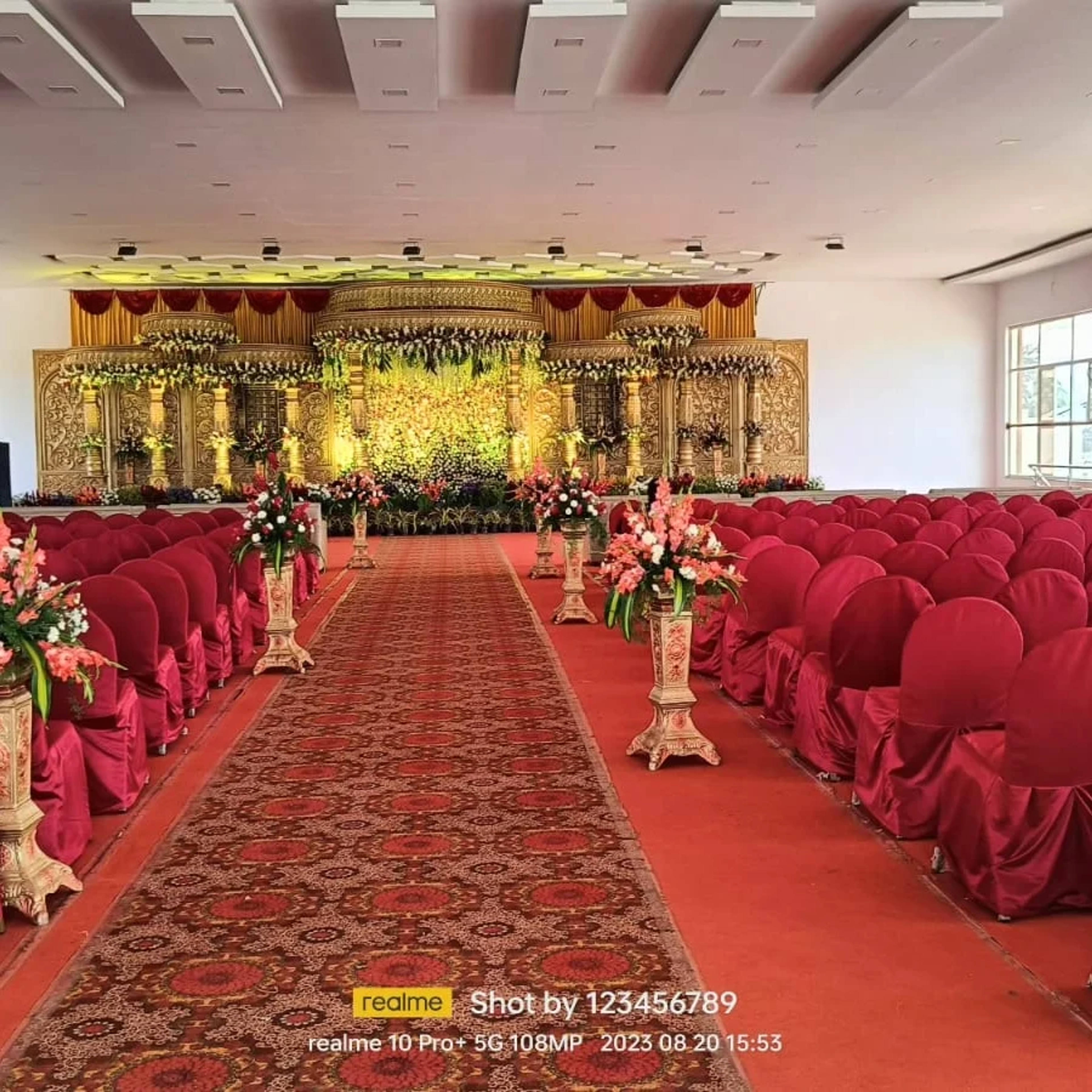 Long banquet aisle with red carpet and draped chairs