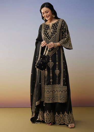 Bold Festive Couple Set – Black Silk Palazzo Suit With Zari Thread And Sequins Work For Her And Black Suiting Jodhpuri Pant Set With Embroidery For Him