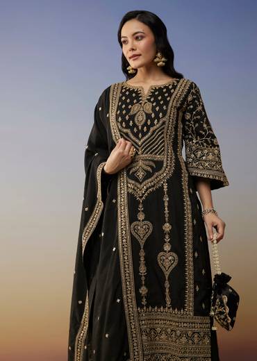 Bold Festive Couple Set – Black Silk Palazzo Suit With Zari Thread And Sequins Work For Her And Black Suiting Jodhpuri Pant Set With Embroidery For Him