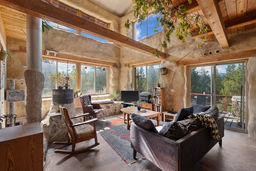 Open and airy living space with large windows and beams.  Rocket wood stove provides plenty of efficient heat.