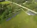 Drone view of ground mounted solar arrays and Rusty Shed with three oversize garage doors.