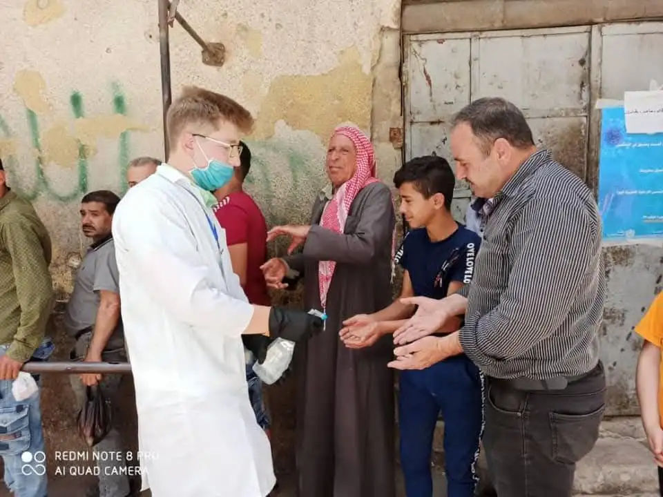 COVID-19 prevention: disinfecting elderly people waiting in line at a bakery