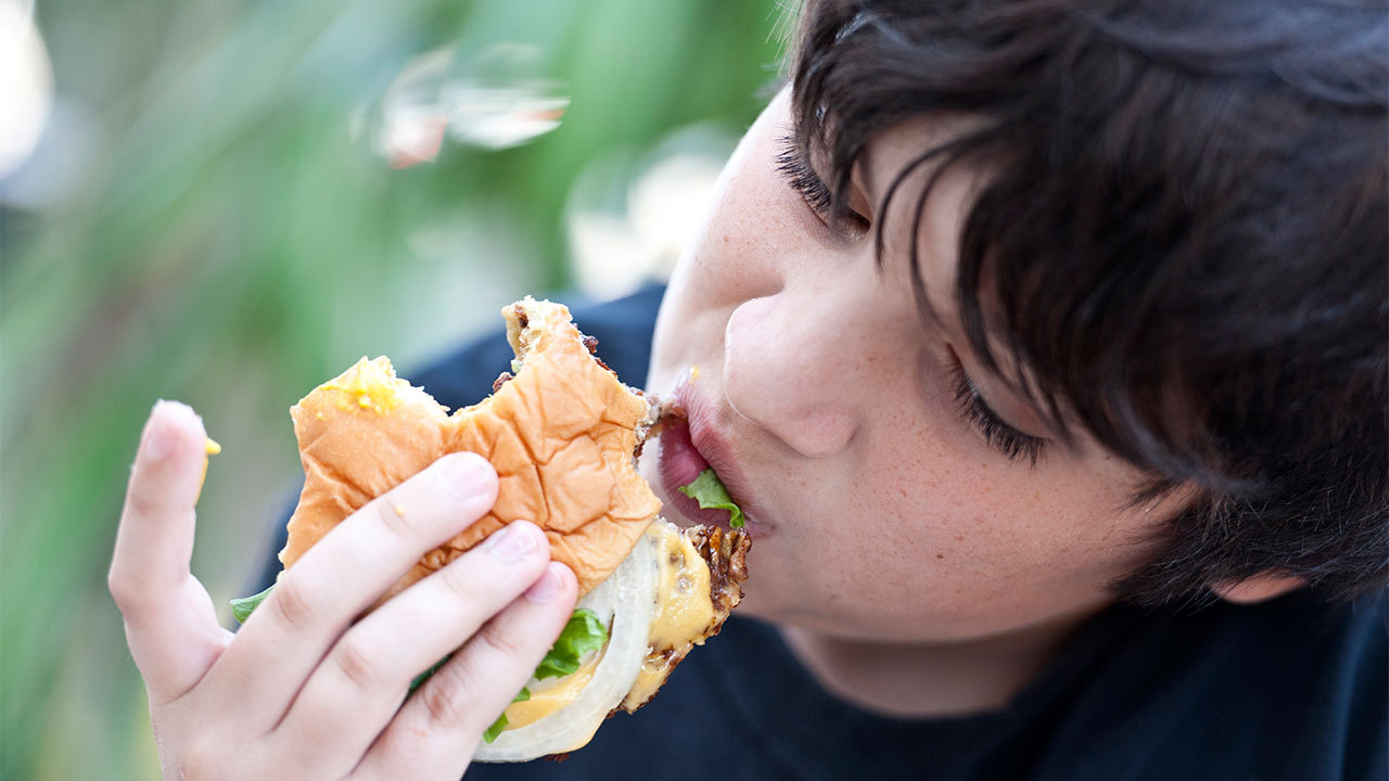 A person eating a sandwich

Description automatically generated