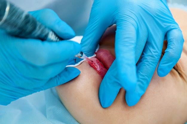 Photo beautician, applies permanent makeup on the lips. lip tattoo