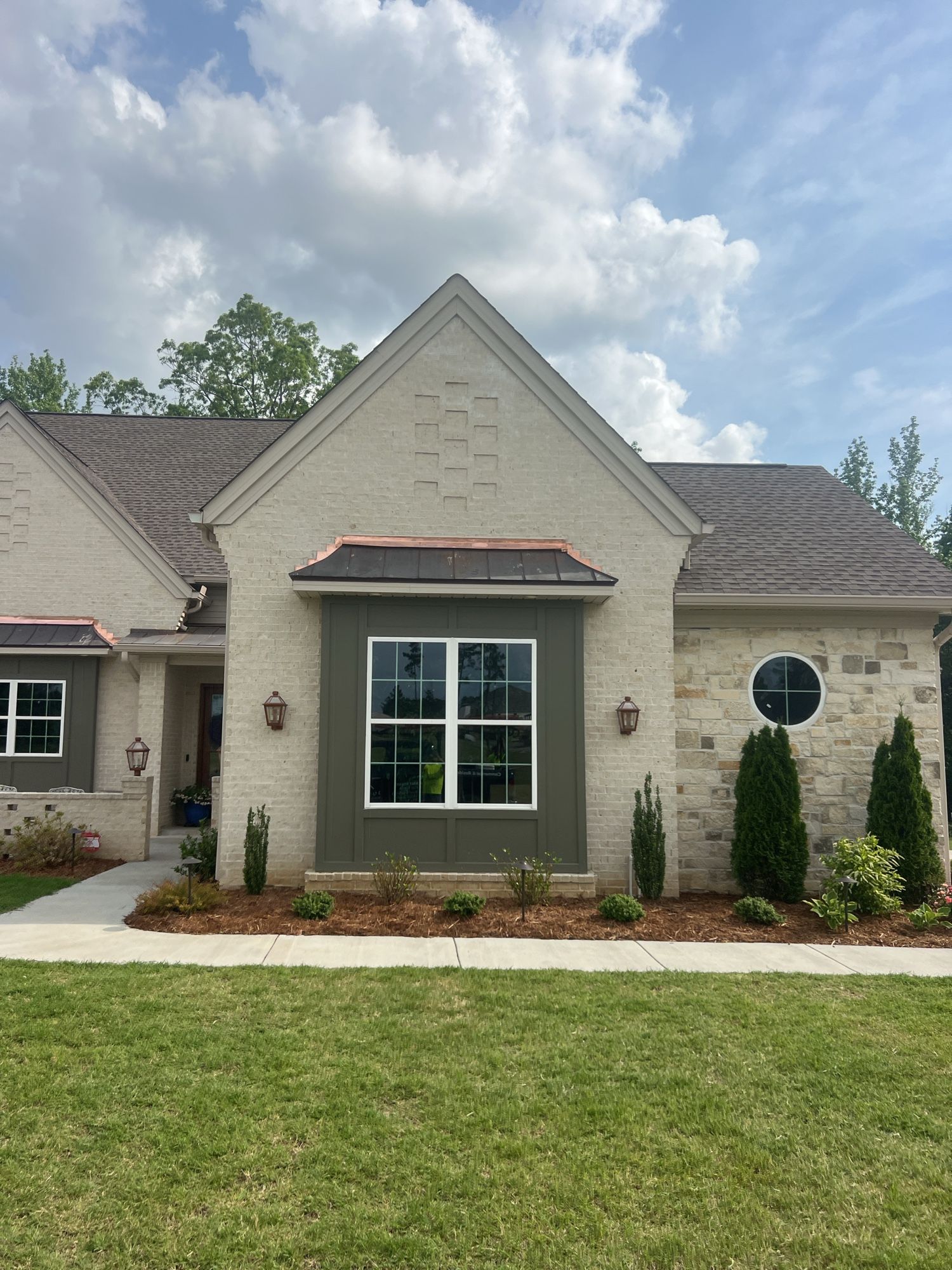 Modern home exterior with stone accents, large front window, and landscaped yard.