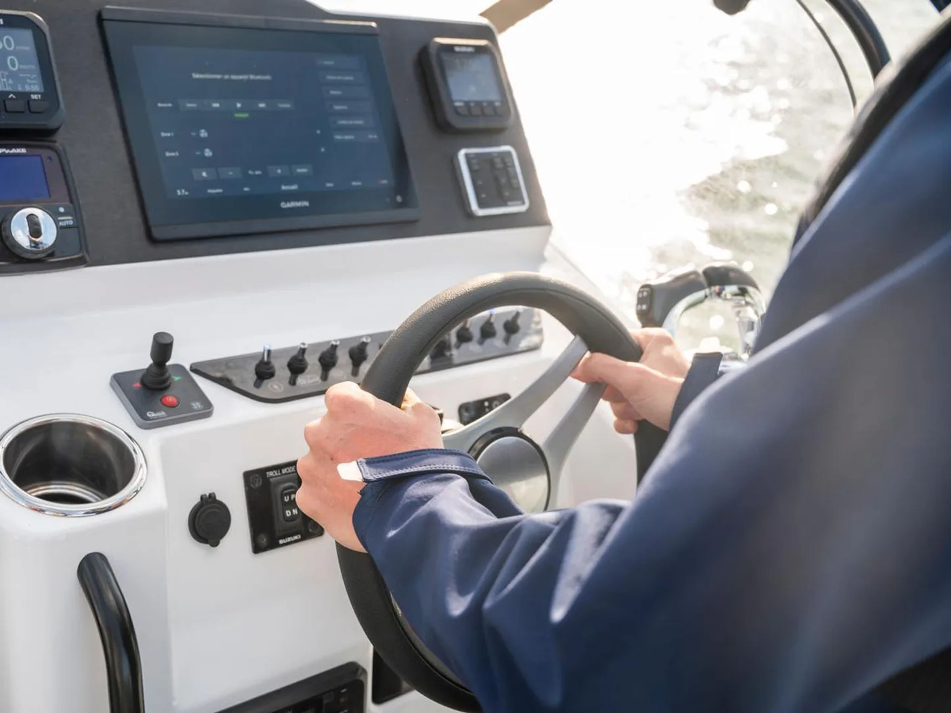 Sailor steering a boat at the helm with modern dashboard instruments