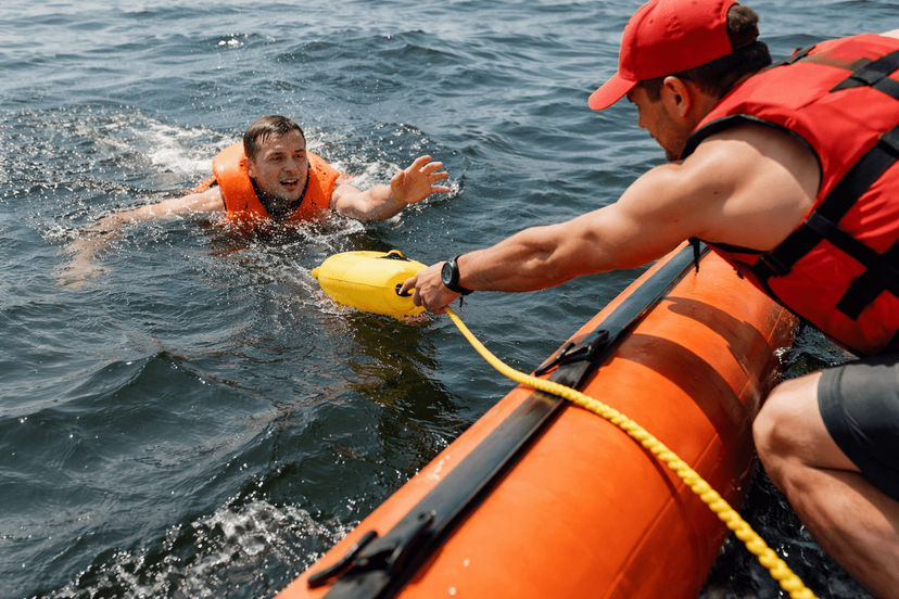 Crew performing immediate man overboard response on a sailboat.