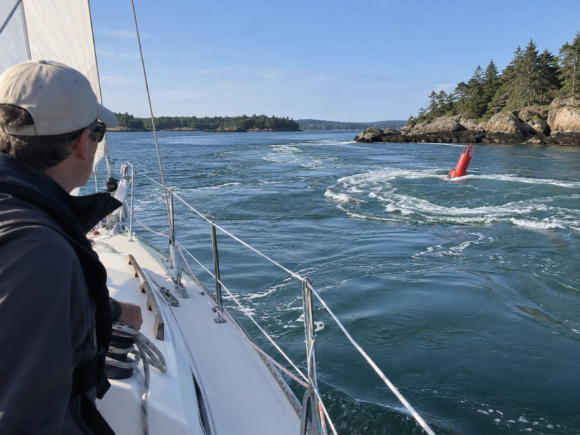 Sailor watching a red buoy leaning in strong current