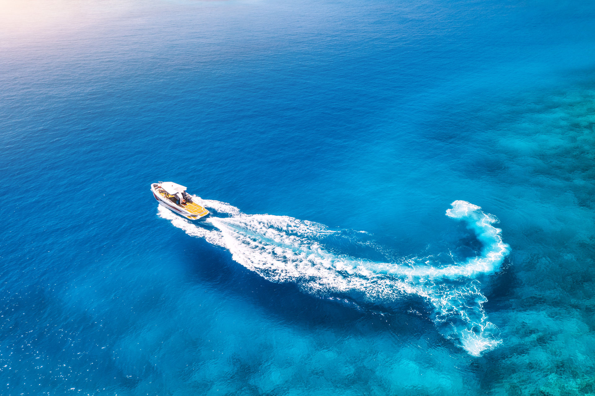Aerial view of a powerboat cruising through clear blue water in Marina del Rey.