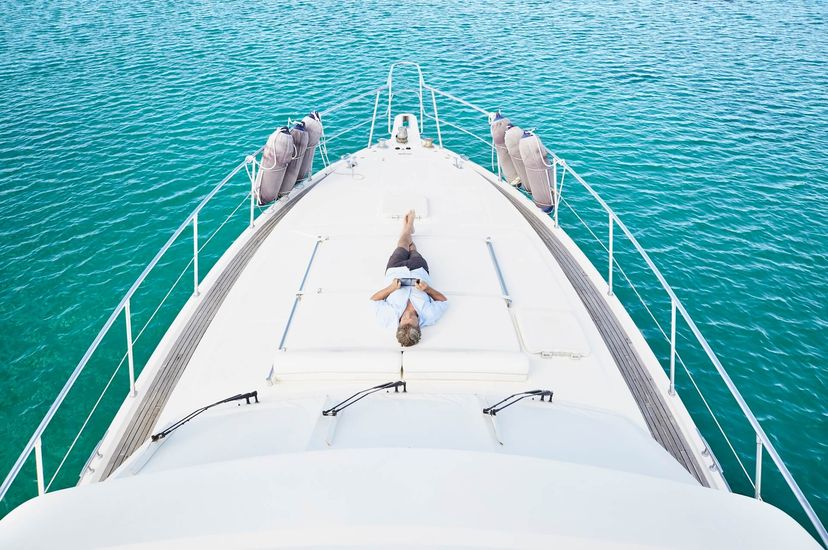 smiling man lying on deck of his motor yacht