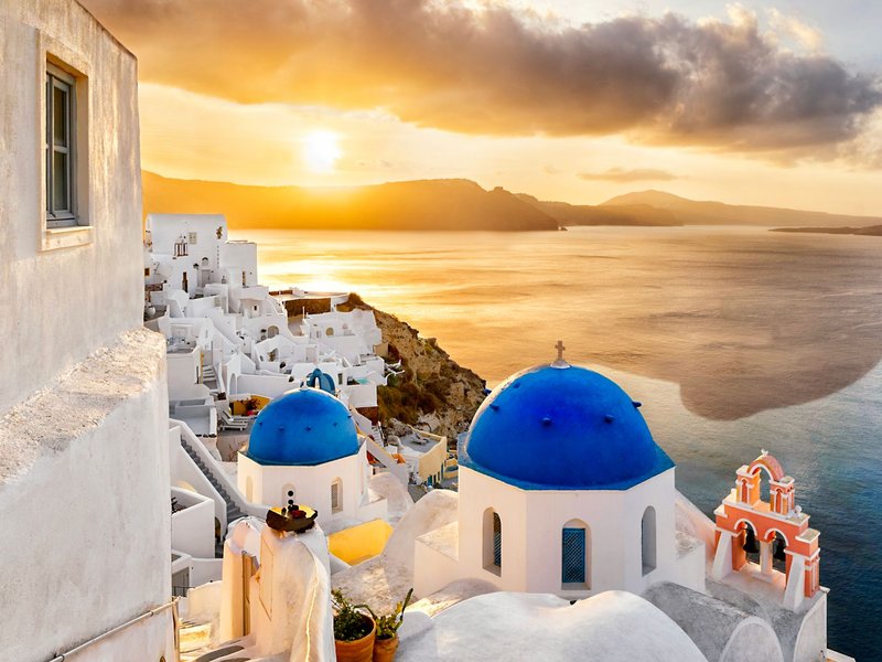 Agence de voyage sur mesure Grèce - Coucher de soleil sur les églises à dômes bleus de Santorin, îles Cyclades