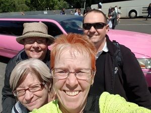 Expert en voyage Sally Stein au premier plan, avec son groupe de voyageurs derrière une photo personnelle.