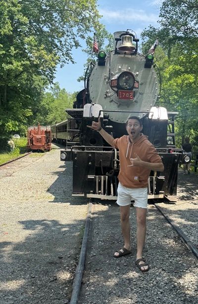 Une photo du Watson Churis souriant, devant le train de la fuite des chemins de fer.