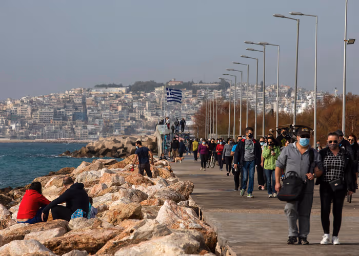 People walk on a promenade at Alimos suburb, south of Athens, Sunday, Jan. 10, 2021. General lockdown measures are extended for a week to Jan.18, and the Greek government has announced the reopening of primary schools and kindergatens as of upcoming Monday. (AP Photo/Yorgos Karahalis)