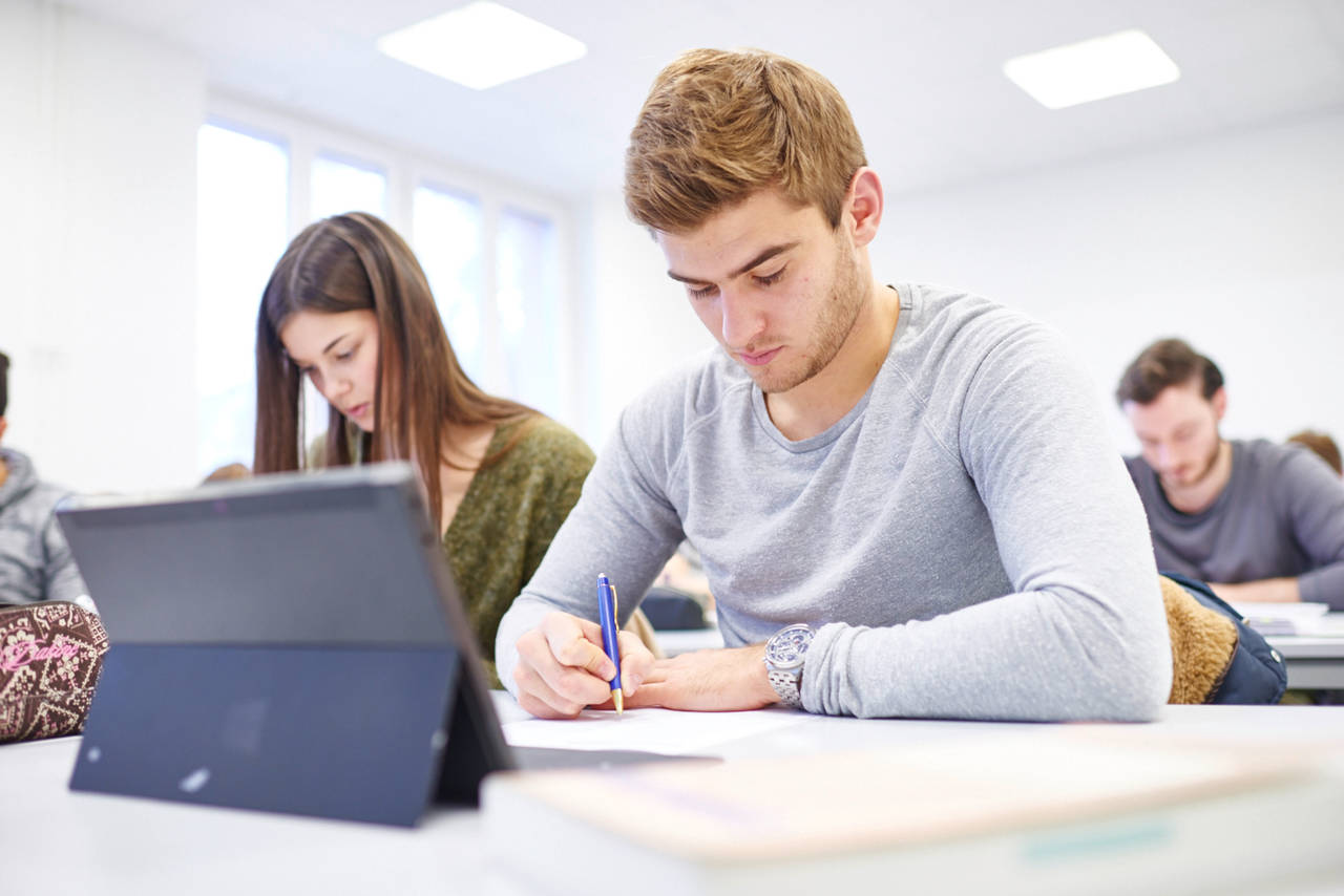 Studierende arbeiten mit Tablet und Notizen