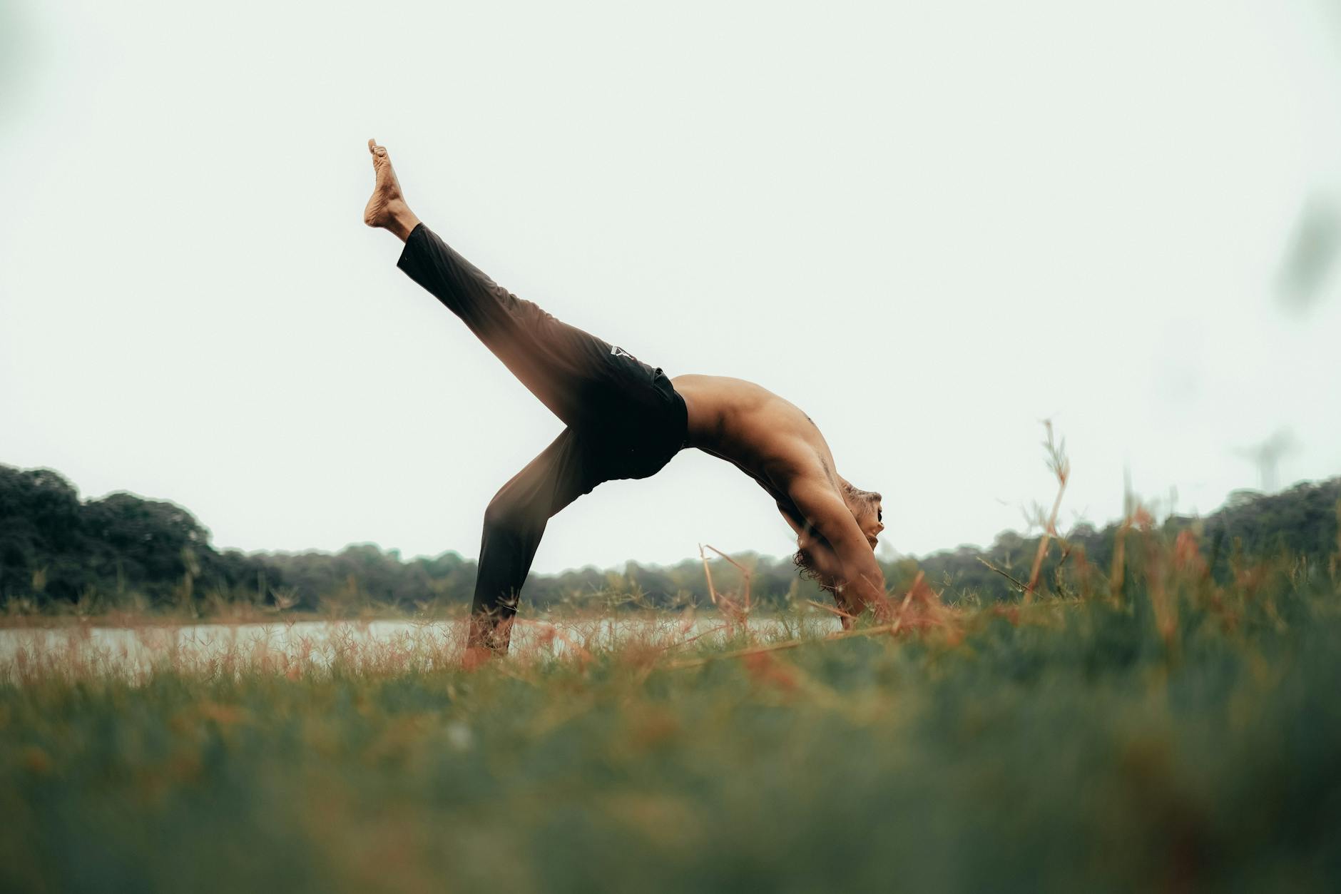 Traveler practicing yoga outdoors overlooking a stadium and lush green sports fields