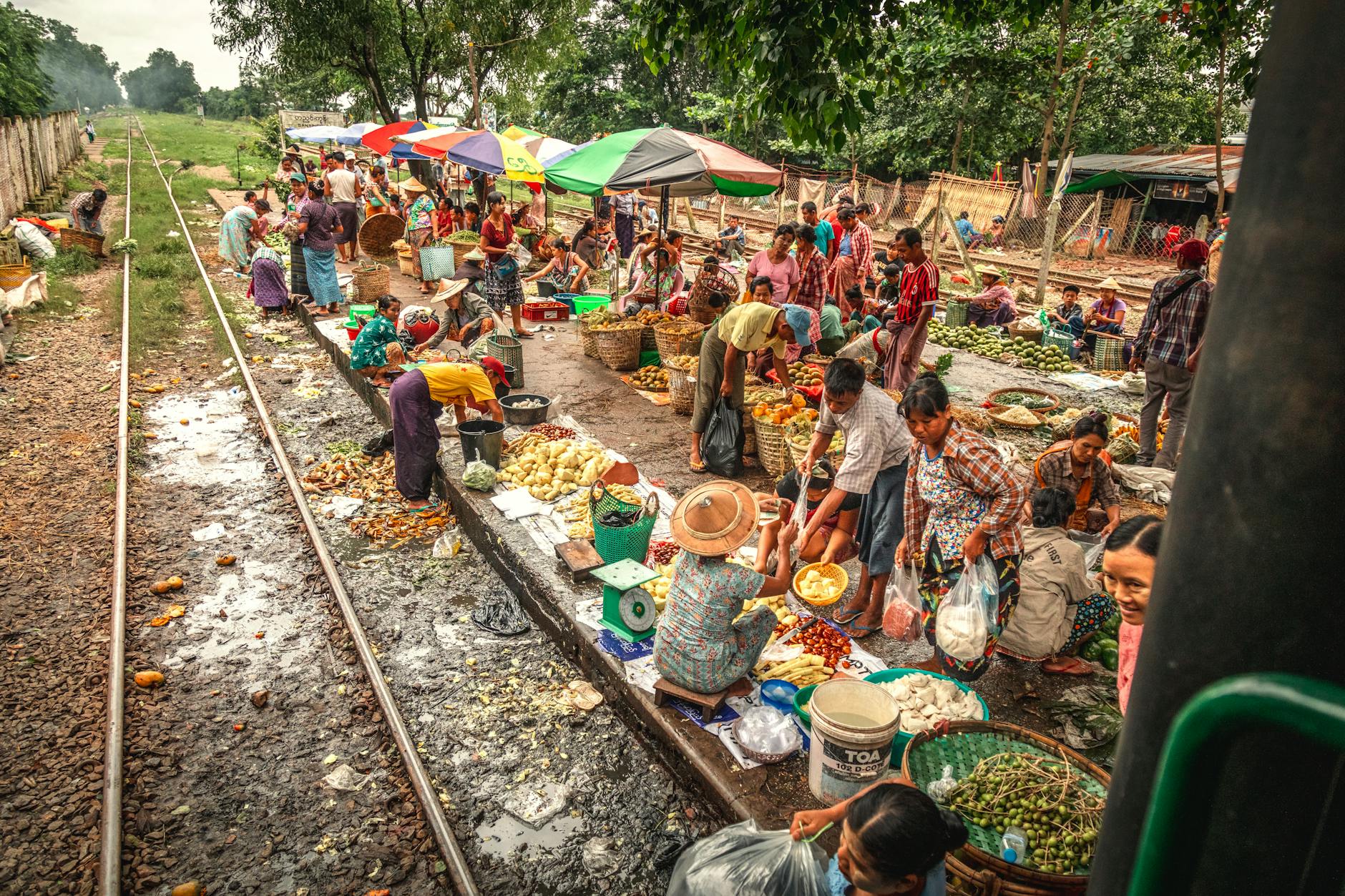 A vibrant street food market with colorful umbrellas under the summer sun.