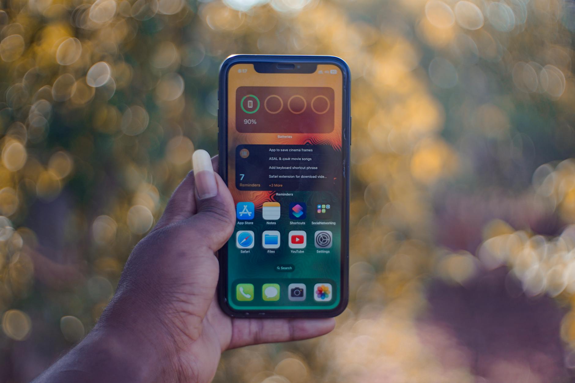 Close-up of hand holding smartphone showing social media apps like Facebook and Instagram.