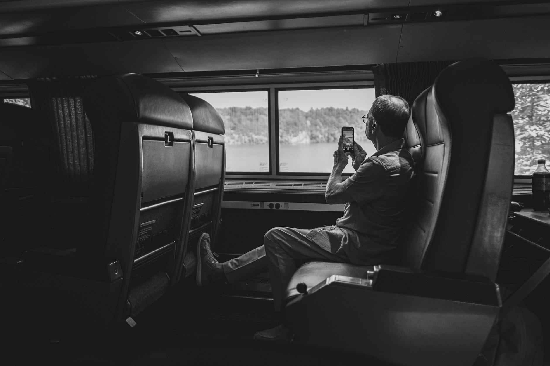 Passenger immersed in landscape views through panoramic windows on serene train route