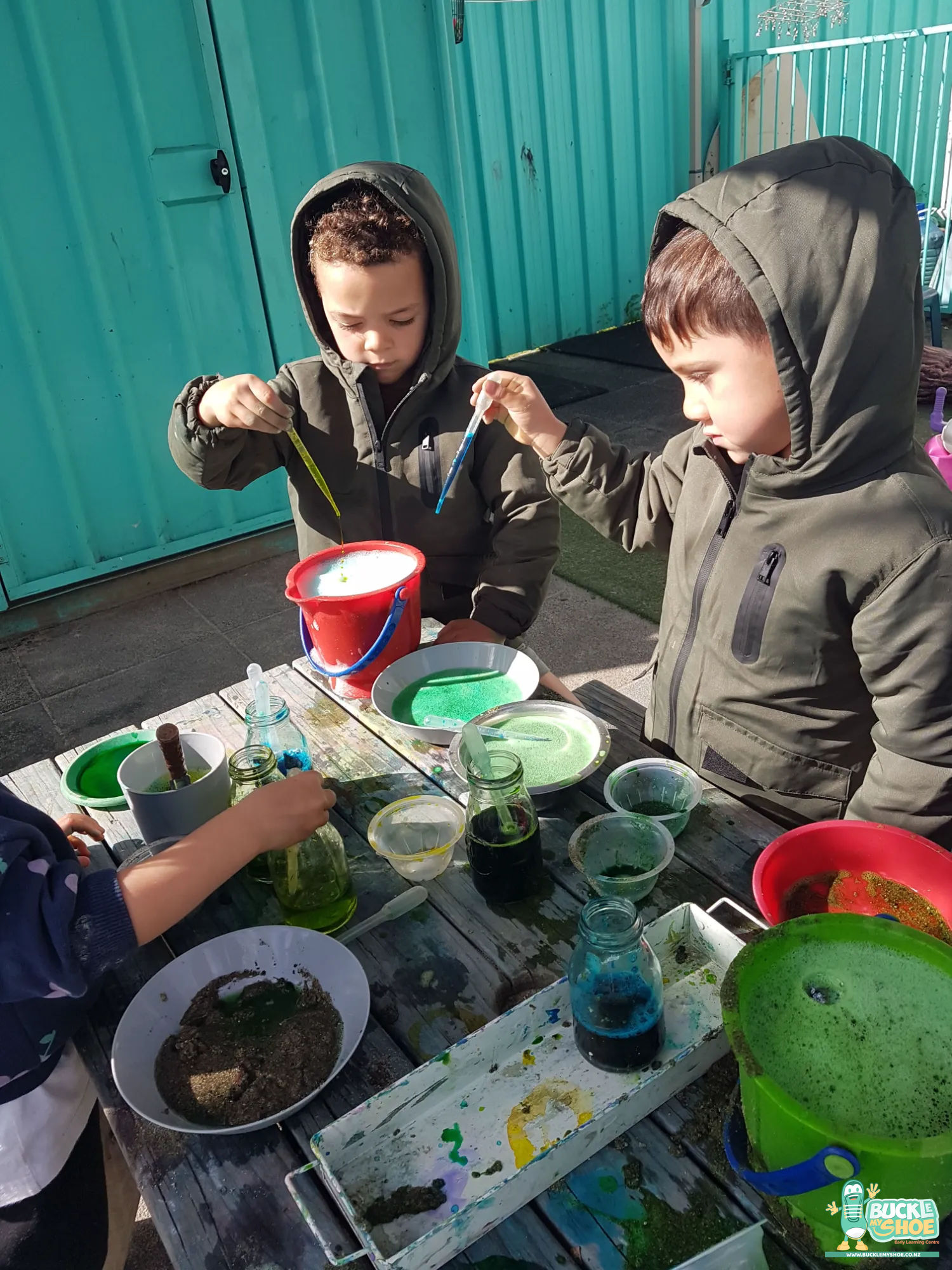 Buckle My Shoe Tauranga & Papamoa | Childcare, Preschool, Daycare | Close up of muddy hands carefully adding secret nature ingredients to liquid.
