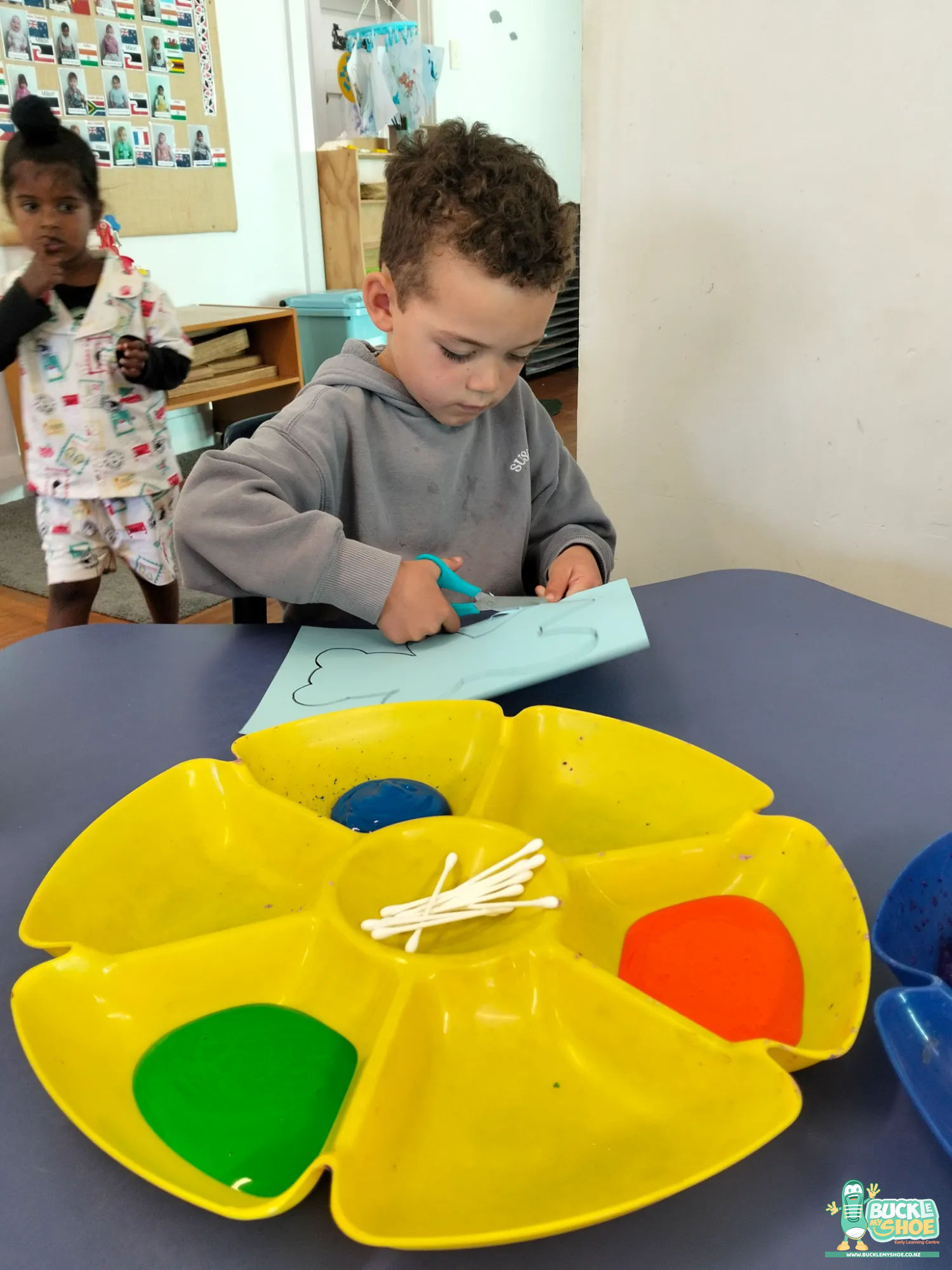 Buckle My Shoe Tauranga & Papamoa | Childcare, Preschool, Daycare | A child carefully gluing decorations onto their teddy bear themed artwork.
