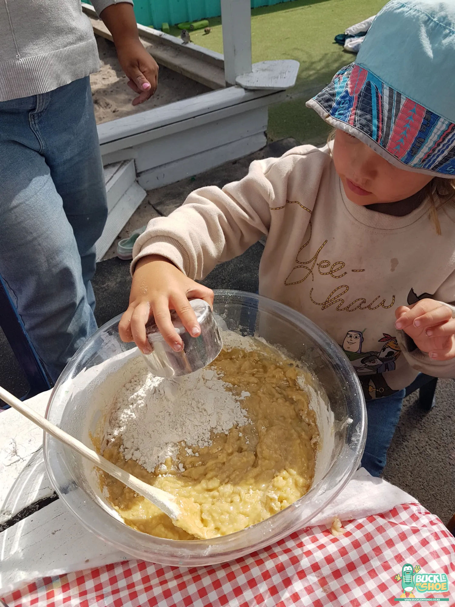Buckle My Shoe Tauranga & Papamoa | Childcare, Preschool, Daycare | A young baker focused intently on rolling out soft dough on bench.