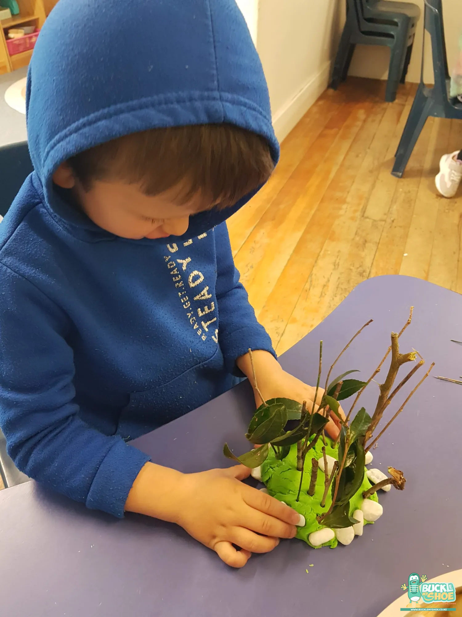 Buckle My Shoe Tauranga & Papamoa | Childcare, Preschool, Daycare | Close up of hands placing natural materials into a soft dough base.