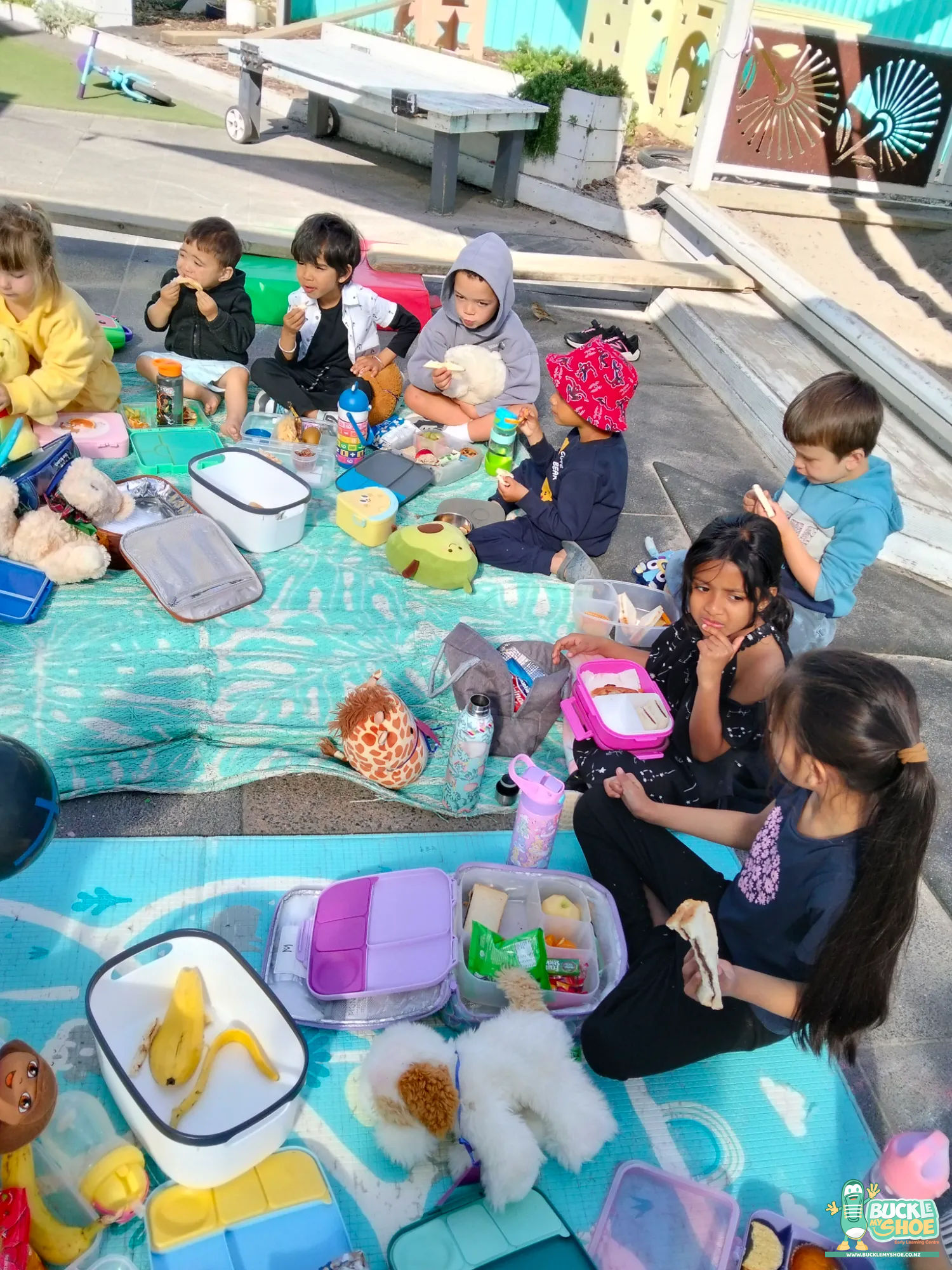 Buckle My Shoe Tauranga & Papamoa | Childcare, Preschool, Daycare | Preschoolers laughing while enjoying donut cookies at the picnic table.