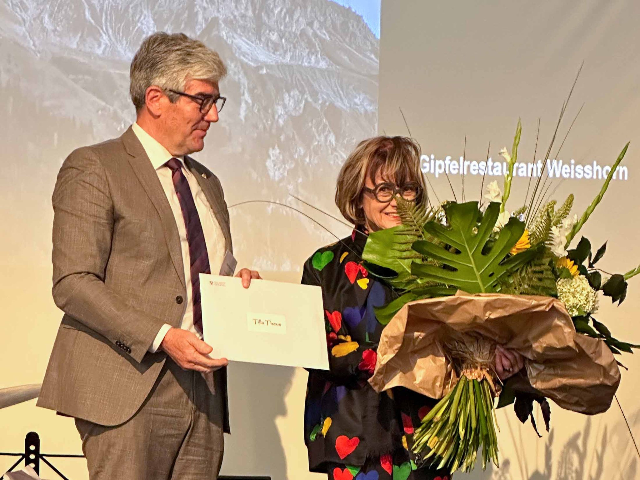 Regierungsrat Jon Domenic Parolini überrreicht Tilla Theus den Graubündner Kulturpreis 2023.