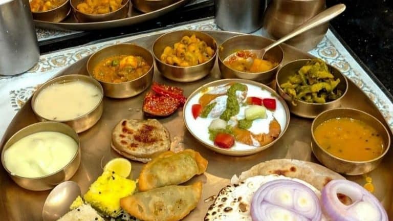 A lavish Gujarati thali with various dishes served in brass bowls.