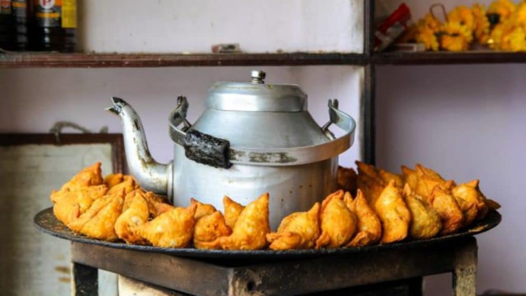 10 Tempting Food Dishes To Relish This Monsoon 1 A collection of samosas with a tea kettle in the background